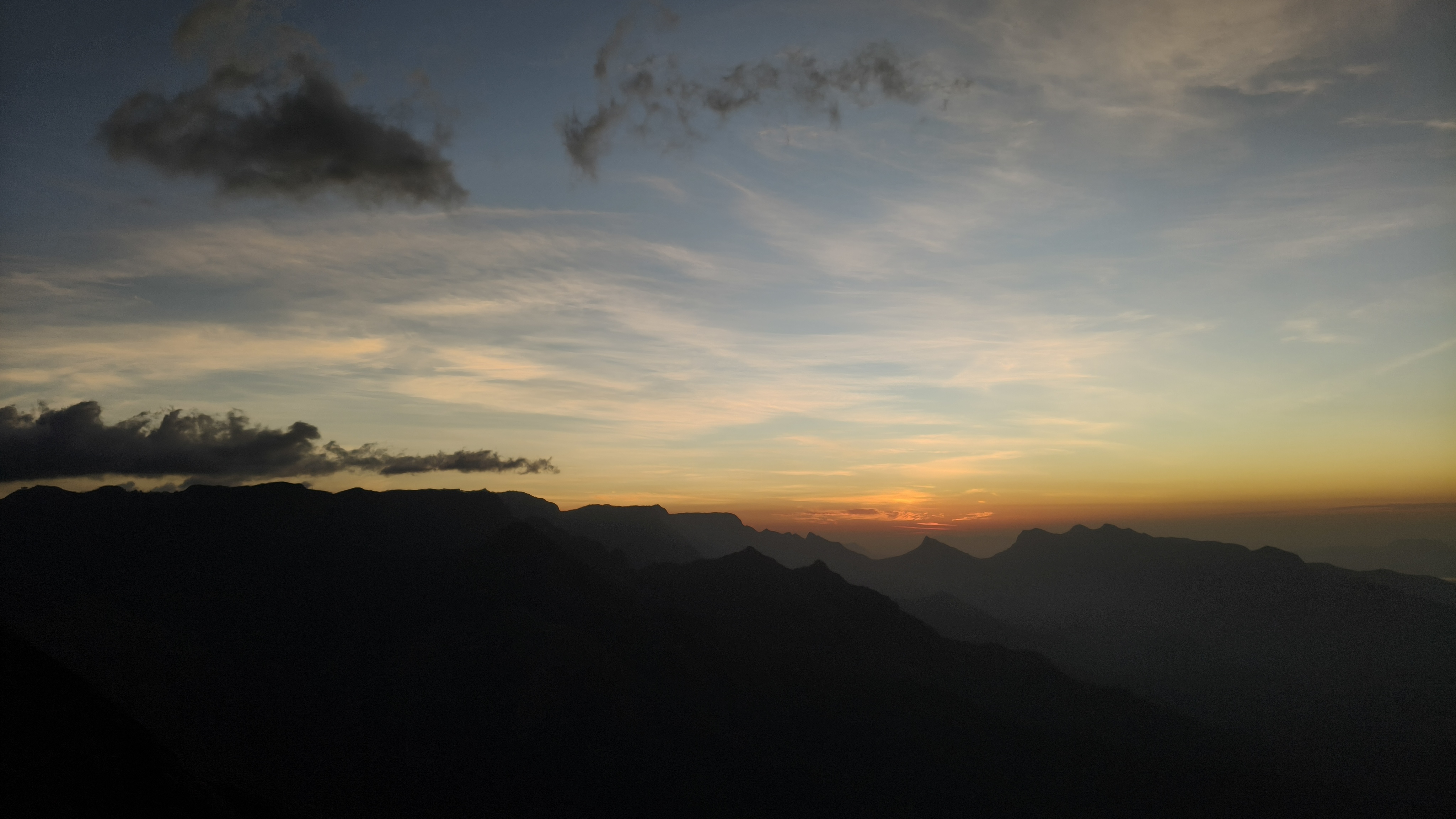 Kolukkumalai morning sky with layered mountains and jeep shadow in foreground